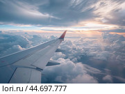Airplane wing flying above clouds at sunset during flight. Стоковое AI-изображение, AI-художник Иван Рябоконь / Фотобанк Лори