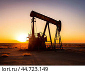 Oil pumping unit against sunset. Pumping unit is a type of surface drives of downhole sucker rod pumps in oil well operation. Стоковое AI-изображение, AI-художник Сергей Елизарьев / Фотобанк Лори