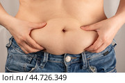 Woman hands pinching her excess belly fat. Obese woman hand holding excessive belly fat, Overweight fatty belly of woman. Стоковое фото, фотограф Павел Муравьев / Фотобанк Лори