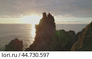 Mountainous landscape with whimsical black rugged cliffs and endless ocean view at sunset. Стоковое видео, видеограф Ольга Сухарева / Фотобанк Лори