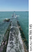 Sea waves crash against an old ruined stone pier breakwater on a sunny afternoon. Волны разбиваются о старый причал в Сочи. Стоковое видео, видеограф Ольга Петрова-Апостолова / Фотобанк Лори