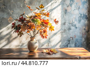 Branches with golden autumn leaves in a ceramic vase on a wooden table by the window. The concept of home comfort. Autumn decor for Halloween. Стоковое AI-изображение, AI-художник Photojuli / Фотобанк Лори