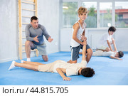 Concentrated boy learning effective self defence techniques in sparring, practicing painful pronating wristlock on male opponent lying face down on floor at sports studio. Стоковое фото, фотограф Яков Филимонов / Фотобанк Лори