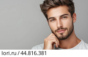 Stylish young man posing casually with a thoughtful expression against a neutral background in a studio setting. Стоковое AI-изображение, AI-художник Сергей Толмачёв / Фотобанк Лори
