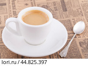 Белая чашка кофе на газете. Мельхиоровая ложка. Стоковое фото, фотограф Александр Рыбалка / Фотобанк Лори