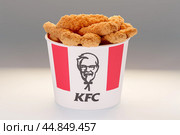 New York, USA - May 31, 2023: KFC basket. Lots of hot wings or strips of KFC chicken in KFC Kentucky Fried Chicken fast food bucket. Редакционная иллюстрация, иллюстратор Павел Муравьев / Фотобанк Лори