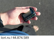 Рука мужчины вынула из кармана пейджер с дисплеем на улице. Портативное беспроводное устройство для приема текстовых сообщений. Редакционное фото, фотограф Sergei Gorin / Фотобанк Лори