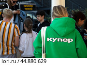 Девушка в брендированной униформе сервиса доставки продуктов питания и товаров из магазинов "Купер" в центре города Москвы, Россия. Редакционное фото, фотограф Николай Винокуров / Фотобанк Лори