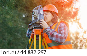A female surveyor engineer with a total station. The geodetic instrument stands next to the geodesy specialist. the concept of conducting engineering and geodesic surveys. Стоковое фото, фотограф Скрипачев Антон / Фотобанк Лори