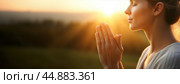 A woman praying peacefully at sunrise, bathed in warm light, symbolizing gratitude and hope for a new beginning. Стоковое AI-изображение, AI-художник Igor Tichonow / Фотобанк Лори