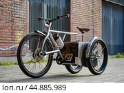 Modern electric cargo tricycle parked on city street. Стоковое AI-изображение, AI-художник Иван Рябоконь / Фотобанк Лори