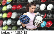 Attentive sporty woman buyer choosing safe bicycle helmet in sports store. Стоковое видео, видеограф Яков Филимонов / Фотобанк Лори