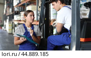 Guy drive operate automatic fork lift loader and answers young female auditors questions. Стоковое видео, видеограф Яков Филимонов / Фотобанк Лори