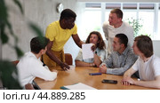 Adult African American tutor, holding sheet of paper, conducting lesson for group of interested men of different nationalities sitting at table in foreign language school classroom. Стоковое видео, видеограф Яков Филимонов / Фотобанк Лори