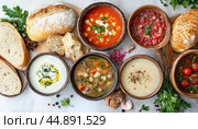 Variety of delicious soups served in bowls for lunch. Стоковое AI-изображение, AI-художник Юрий Поздников / Фотобанк Лори
