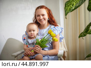 A woman with long red hair and a young girl in matching blue striped dresses with colorful tassels. Family posing for photo shoot. Стоковое фото, фотограф Кривошеина Елена Леонидовна / Фотобанк Лори