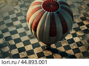 Hot air balloon taking off from checkerboard patterned ground. Стоковое AI-изображение, AI-художник Иван Рябоконь / Фотобанк Лори
