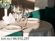 Stylish table setting. Glass glasses, plates, cutlery on the table. Wedding service, reception at the dining table. A birthday, a baptism, a festive event. Стоковое фото, фотограф Photojuli / Фотобанк Лори