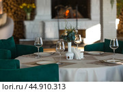 Stylish table setting. Glass glasses, plates, cutlery on the table. Wedding service, reception at the dining table. A birthday, a baptism, a festive event. Стоковое фото, фотограф Photojuli / Фотобанк Лори
