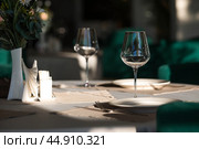 Stylish table setting. Glass glasses, plates, cutlery on the table. Wedding service, reception at the dining table. A birthday, a baptism, a festive event. Стоковое фото, фотограф Photojuli / Фотобанк Лори
