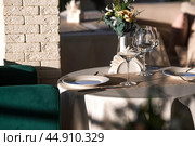 Stylish table setting. Glass glasses, plates, cutlery on the table. Wedding service, reception at the dining table. A birthday, a baptism, a festive event. Стоковое фото, фотограф Photojuli / Фотобанк Лори