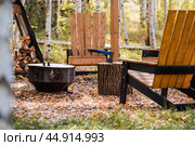 Eco-friendly, stylish barbecue area and wooden chairs for relaxing by the campfire. An axe will be stuck into a wooden log. Chopping firewood. Стоковое фото, фотограф Photojuli / Фотобанк Лори