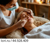 The beautician applies a cleansing clay mask to the girl's face while she lies in the chair. It gently exfoliates dead cells, smoothes the texture and evens out the tone. Стоковое AI-изображение, AI-художник Сергей Елизарьев / Фотобанк Лори