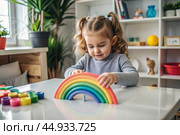 Toys. A little girl is playing educational games. A rainbow-shaped children's toy, colored pyramids and logic toys for children. Montessori games for child development. Стоковое AI-изображение, AI-художник Photojuli / Фотобанк Лори
