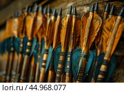 Row of traditional wooden arrows with blue fletching and metal tips. Стоковое AI-изображение, AI-художник Иван Рябоконь / Фотобанк Лори