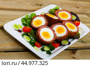 Scotch eggs served with greens and leek, Scottish traditional dish at plate. Стоковое фото, фотограф Яков Филимонов / Фотобанк Лори