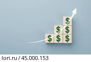 Wooden blocks with US dollars. concept of revenue growth. growth on stacked wooden cubes on blue background. arrow and dollar icons on wooden cubes. copy space. Стоковое фото, фотограф Павел Муравьев / Фотобанк Лори