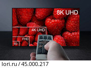 Comparing TV resolutions on television screen. TV ultra HD resolution. 8K resolutions compare on oled tv. Watching television in TV room. Compare of television resolution. hand with remote control. Стоковое фото, фотограф Павел Муравьев / Фотобанк Лори