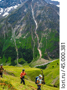 Alps, Italy - August 13, 2023: Mountain trekking. Hikers with trekking sticks climbs steep on mountain trail. Mountain landscape. Tourism, sport life style concept. Стоковое фото, фотограф Павел Муравьев / Фотобанк Лори