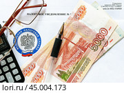Время платить налоги. Налоговое уведомление, деньги, калькулятор, очки и эмблема Федеральной налоговой службы.  Крупный план. Стоковое фото, фотограф Лариса Гордеева / Фотобанк Лори