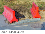 Vibrant red plastic barrier surrounds a deep excavation for a well, symbolizing both the potential for life-giving water and the hidden dangers of neglecting safety. Стоковое фото, фотограф Татьяна Степанищева / Фотобанк Лори