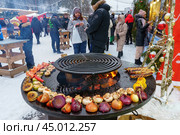 Holiday fair on the street in winter in the city. Cooking vegetables on the grill at the festivities (2024 год). Редакционное фото, фотограф Zima Nadezhda / Фотобанк Лори