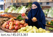 Young Muslim woman in niqab choosing apples in store. Стоковое фото, фотограф Яков Филимонов / Фотобанк Лори