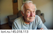 Elderly man with cognitive decline sitting alone in room, looking confused and lost, wearing casual clothes, showing signs of memory loss, feeling isolated and sad. Стоковое AI-изображение, AI-художник Павел Муравьев / Фотобанк Лори