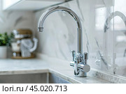 Kitchen sink. Modern new faucet, marble countertop. Stylish white sink, faucets in a light interior. Chrome steel tap. Domestic Appliances. Gray clean bright household equipment. Contemporary style. Стоковое AI-изображение, AI-художник Марина Демидюк / Фотобанк Лори