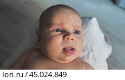 Close-up of a baby lying on its back. The baby has a curious and slightly confused expression, wide open blue eyes, partially open mouth. The newborn gestures to show that he wants to eat. Стоковое видео, видеограф Воловодов Владимир / Фотобанк Лори