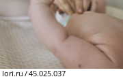 Close-up of a baby being changed. A blurred video. Mum's hands fasten the nappy on a newborn baby. Стоковое видео, видеограф Воловодов Владимир / Фотобанк Лори