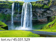 Seljalandsfoss waterfall cascading from volcanic cliffs covered in lush green moss in iceland. Стоковое AI-изображение, AI-художник Иван Рябоконь / Фотобанк Лори