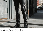 Fashionable man wearing black leather pants and chelsea boots standing on city sidewalk. Стоковое AI-изображение, AI-художник Иван Рябоконь / Фотобанк Лори