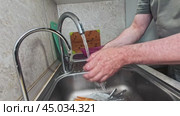 The man turns on the faucet in the kitchen and checks the temperature of the water and then washes his hands. Стоковое видео, видеограф Ярославский Максим / Фотобанк Лори