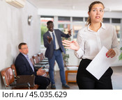 Upset young woman standing in waiting room with her back to person who is shouting at her. Стоковое фото, фотограф Яков Филимонов / Фотобанк Лори