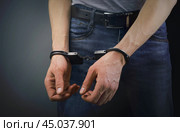Arrested man standing forward in handcuffs on gray background. Стоковое фото, фотограф Дмитрий Кобзев / Фотобанк Лори