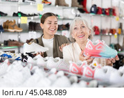 Elderly mom strongly recommends her doughter to pay attention to classic model of light sneakers. Стоковое фото, фотограф Яков Филимонов / Фотобанк Лори