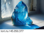 Large blue celestite crystal cluster sitting in sunbeam on windowsill. Стоковое AI-изображение, AI-художник Иван Рябоконь / Фотобанк Лори