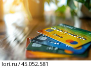 Stack of colorful credit cards sitting on wooden desk. Стоковое AI-изображение, AI-художник Иван Рябоконь / Фотобанк Лори