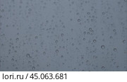 Heavy raindrops tapping on the window pane. Raindrops flowing down the window pane during a downpour. Rainy weather. Капли дождя стучат по стеклу во время ливня. Стоковое видео, видеограф Ольга Петрова-Апостолова / Фотобанк Лори